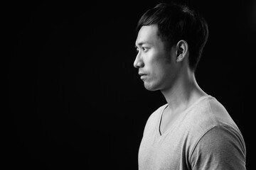 Young handsome Asian man against black background