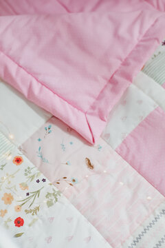 Cozy baby cot with pink patchwork blanket. Baby bedding. Baby crib, close up. Textile for children nursery. Nap and sleep time