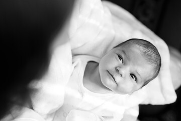 Black and white photo. Loving mom carying of her newborn baby at home. Woman holds and hugs her...