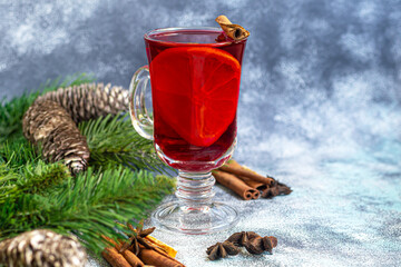Mulled wine, a warming drink in a cup with spices. Christmas toys. New Year mood. On a light background.
