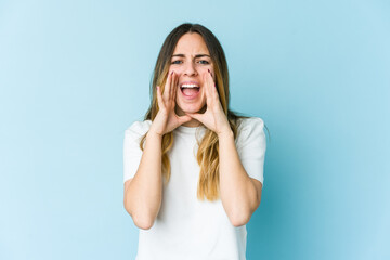 Young caucasian woman isolated on blue background shouting excited to front.