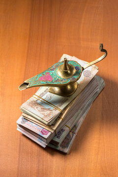 Heap of UAE Dirham currency notes with an antique Aladdin lamp. A conceptual image for 'Dream big' or 'Get lucky'.