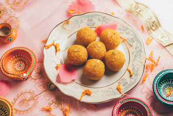 Bundi Laddu served in a plate along with traditional Indian Diyas. An Indian festive food and background.