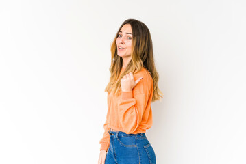 Fototapeta premium Young caucasian woman isolated on white background points with thumb finger away, laughing and carefree.