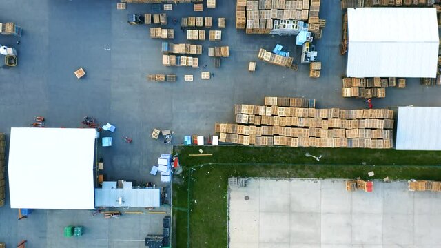 Outside storage (storage yard) of wooden pallets in logistics park with warehouse. Aerial top down view