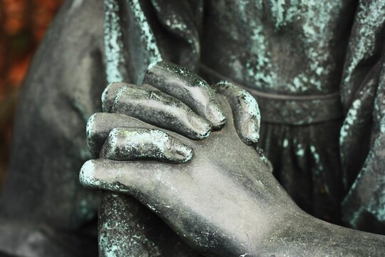 Hands of a praying statue close up