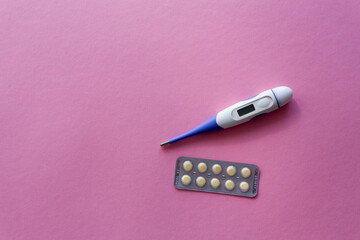 Electronic thermometer on a pink background. The medicine. Macro photography, soft focus.