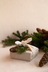 New Year's gift packed in an eco-friendly white cotton fabric wrap with a spruce branch and a pine cone