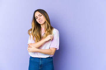 Young caucasian woman isolated on purple background massaging elbow, suffering after a bad movement.