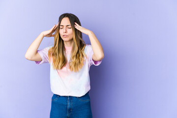 Fototapeta premium Young caucasian woman isolated on purple background touching temples and having headache.