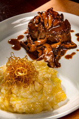 Beef with risotto and shitake sauce on a white plate