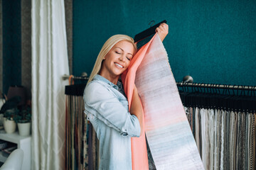 Fototapeta na wymiar Young woman designer chooses fabrics for curtains in textile show room.