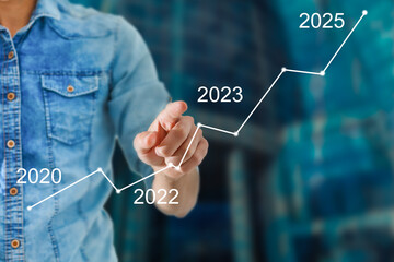 Man's hand pointing graph of success in 2023 year. Growing business concept