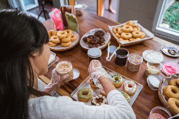 women wear aprons while decorating donuts on the table in the kitchen