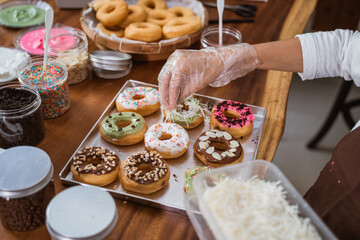 hands wearing plastic gloves decorate the donuts with cheese on the wooden table