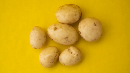 Various raw potatoes on a yellow background