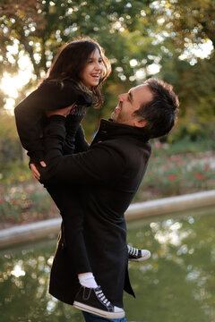 padre juega con su hija alzándola en brazos en exteriores 