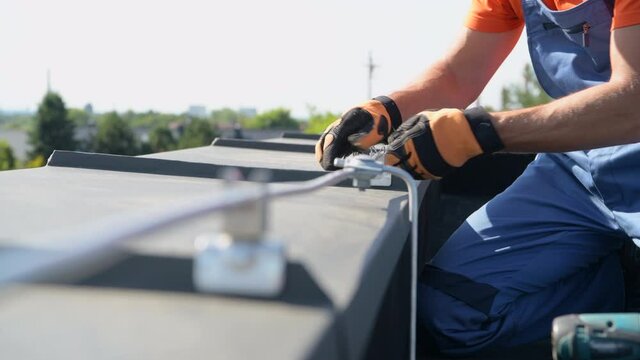 Caucasian Technician Adjusting Metal Rod of Lightning Protection System Working on the Top of the Building.