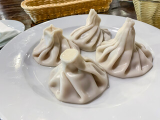 Hot juicy khinkali with meat and herbs on white plate