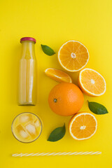 Top view of orange juce and oranges on the yellow  background