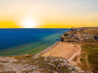 Fototapeta na wymiar emerald sea bay with stony coast at the sunset