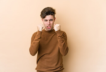 Young caucasian man isolated on beige background upset screaming with tense hands.