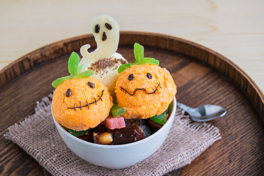 Halloween dessert in a white cup. It consists of ice cream in the form of a ghost pumpkin and a  chocolate white ghost.  Creative food for the holiday and good mood..