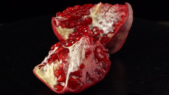 Broken pomegranate fruit close up on black background