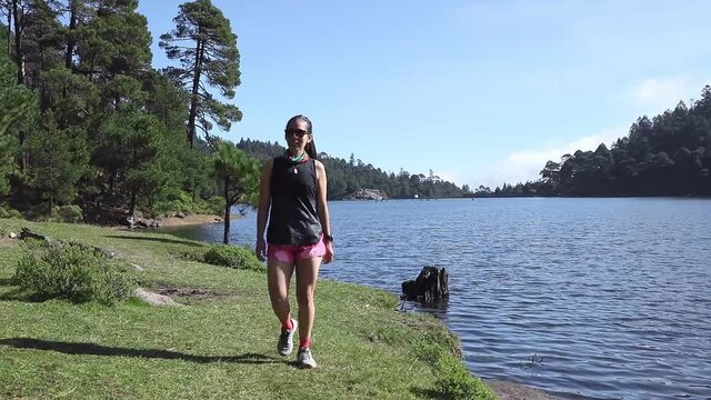 Mujer caminando cerca de un lago al aire libre en la monta&ntilde;a, despu&eacute;s de hacer entrenamiento de resistencia. Estilo de vida saludable y disciplina deportiva