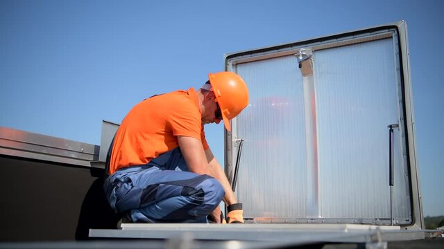 Caucasian Technician in His 40s Assembling Roof Entrance on Building Roof