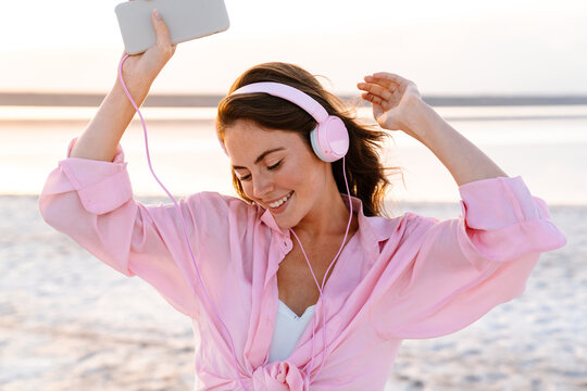 Optimistic young girl in sunglasses listening music