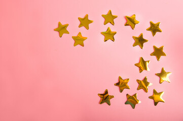  Gold stars confetti on a pink background. Golden  confetti close-up and copy space.