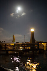 Fototapeta na wymiar Harbor at Night with Boats Full Moon and Lighthouse 
