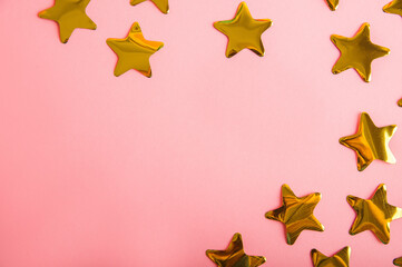 Gold stars confetti on a pink background. Golden  confetti close-up and copy space.