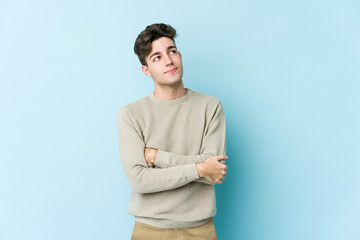 Young caucasian man isolated on blue background dreaming of achieving goals and purposes