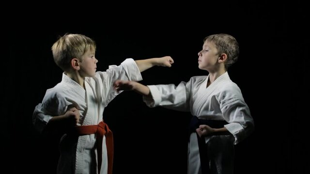 With orange and blue belt, two athletes doing paired exercises on a black background