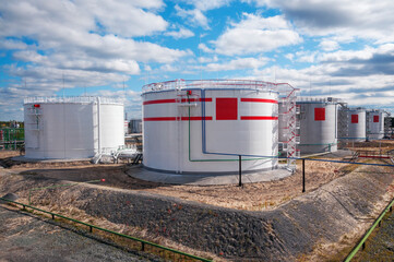 Obraz premium Cloudy day. Tanks with oil for further transportation of oil through pipes at an oil refinery and oil pumping station