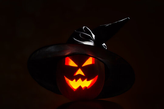 Halloween pumpkin smile and scary eyes in a black cap. View of s
