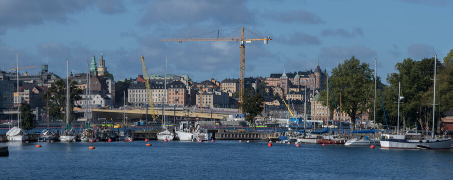 Boats and landmarks in a panorama view of the districts Södermalm and the old town Gamla Stan also the bridge Guld Bron a sunny morning in a Stockholm