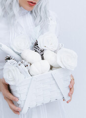 Young Magic Girl in white space holds winter Christmas decor box. Minimal fashion festive Christmas / New Year holidays celebration concept.