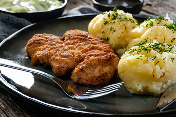 Pork chop served with mashed potatoes and cucumber salad.