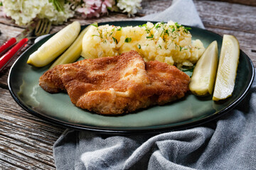 Pork chop served with mashed potatoes and pickled cucumber.