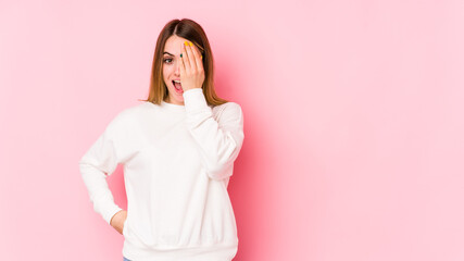 Young caucasian woman isolated on pink background having fun covering half of face with palm.