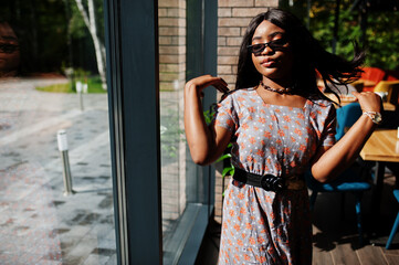 Fashion portrait of african american woman in long dress and eyeglasses indoor.