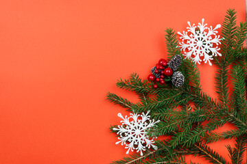 Christmas background with branches and decorations on a red table.