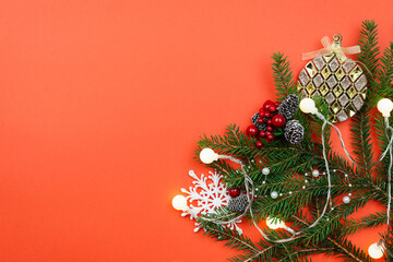 Christmas background with branches and decorations on a red table.