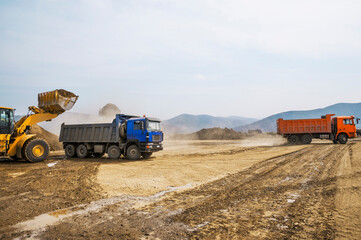 Wheel loader loads clay into the bucket of a dump truck