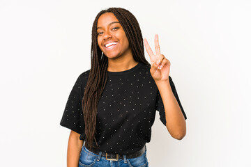 Young african american woman isolated on white background showing victory sign and smiling broadly.