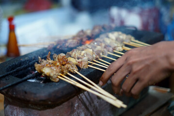 Street food vendor prepares grill Satay Padang at night market