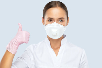 A doctor in a white coat, a mask on his face and rubber pink gloves. Medical concept, Covid-19. The doctor shows the class!